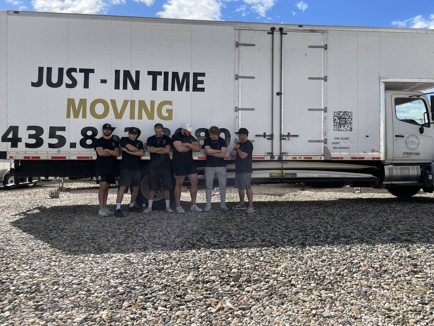 The full Just-In Time Moving crew lined up in front of two branded moving trucks in St. George, Utah